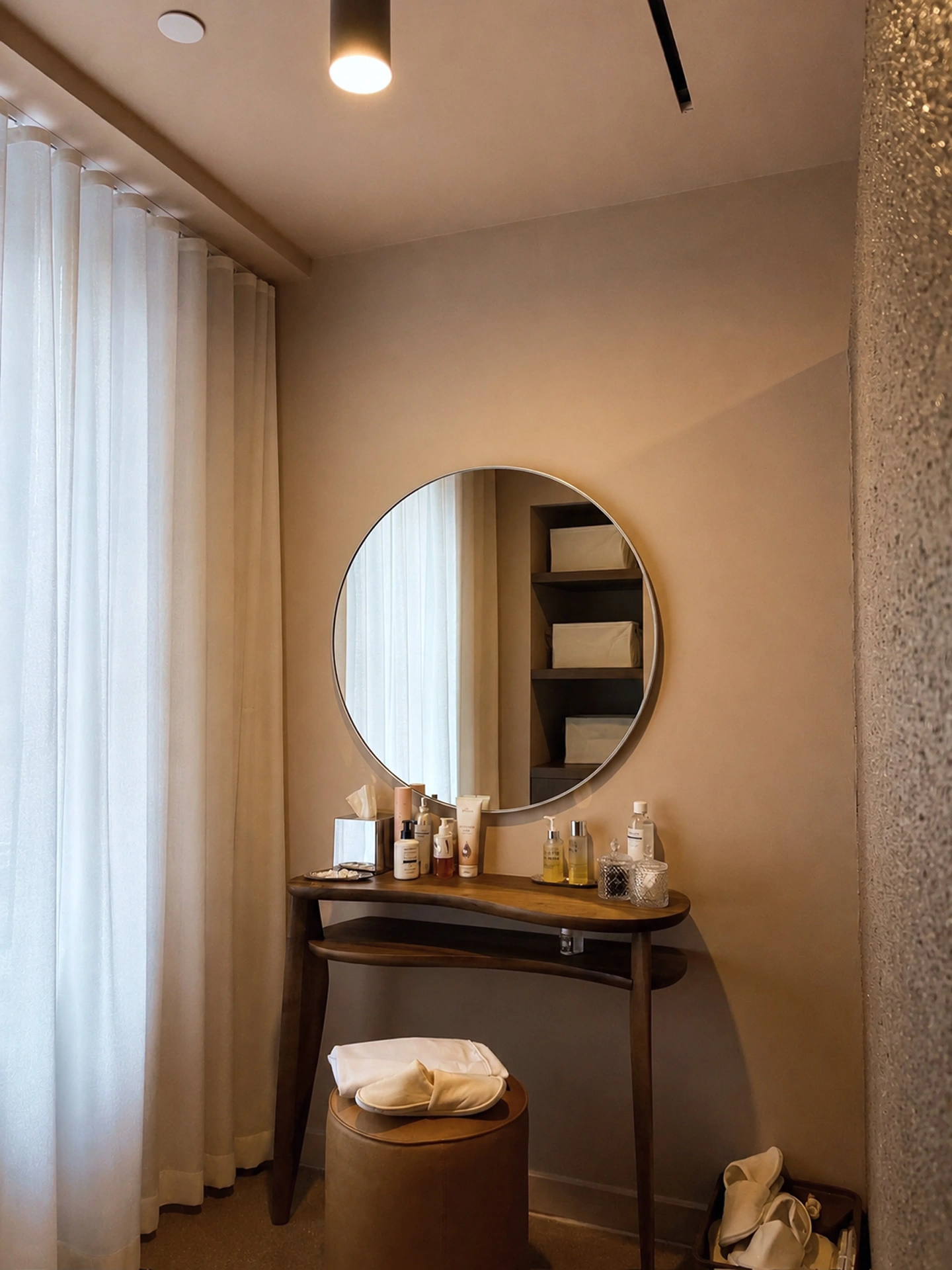 Vanity with round mirror, curated amenities and a velvet stool at Zohar