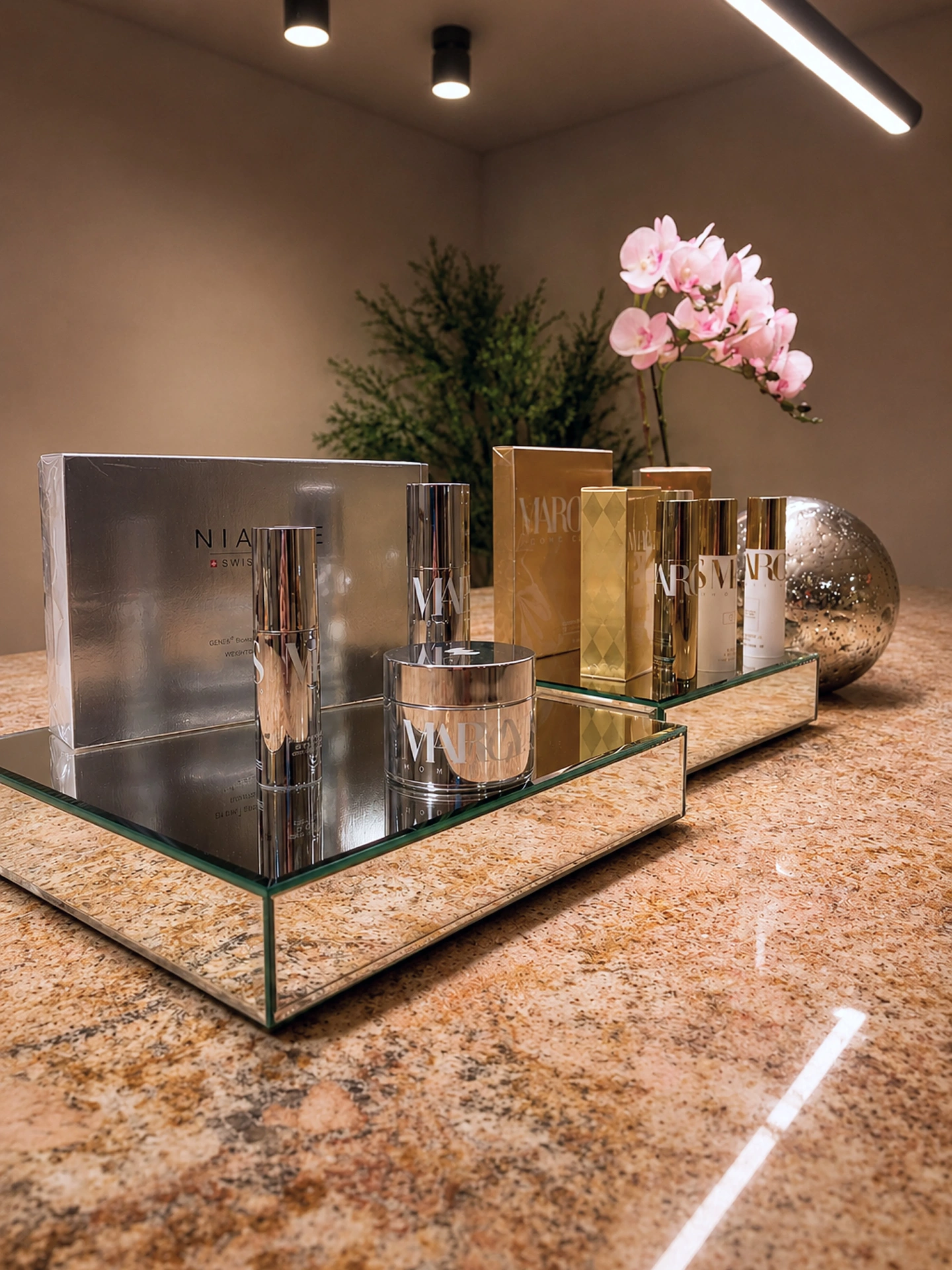 Mirrored trays of Niance and Margy's luxury skincare with orchids at Zohar