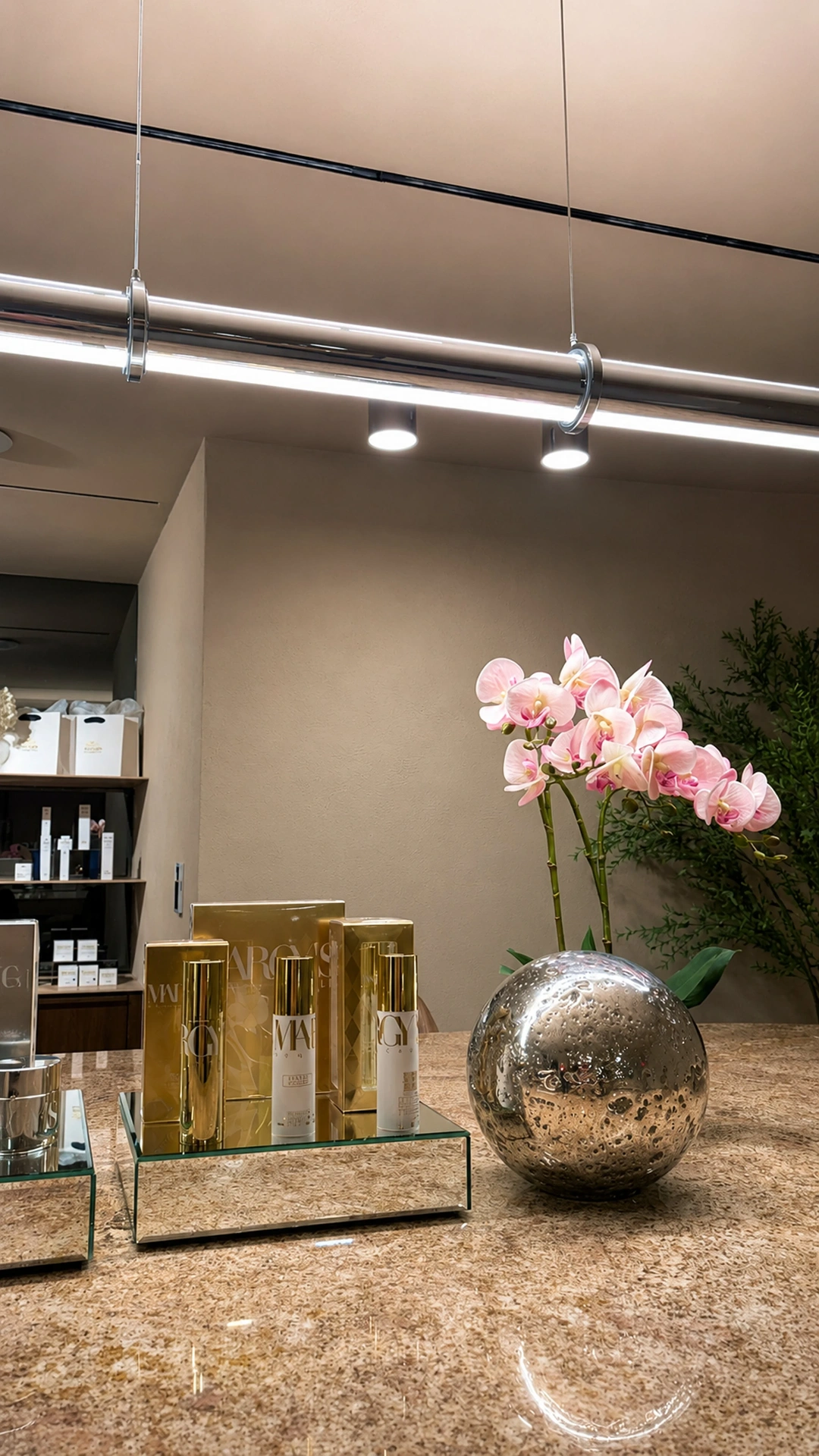 Boutique counter with gold Margy's skincare and pink orchids
