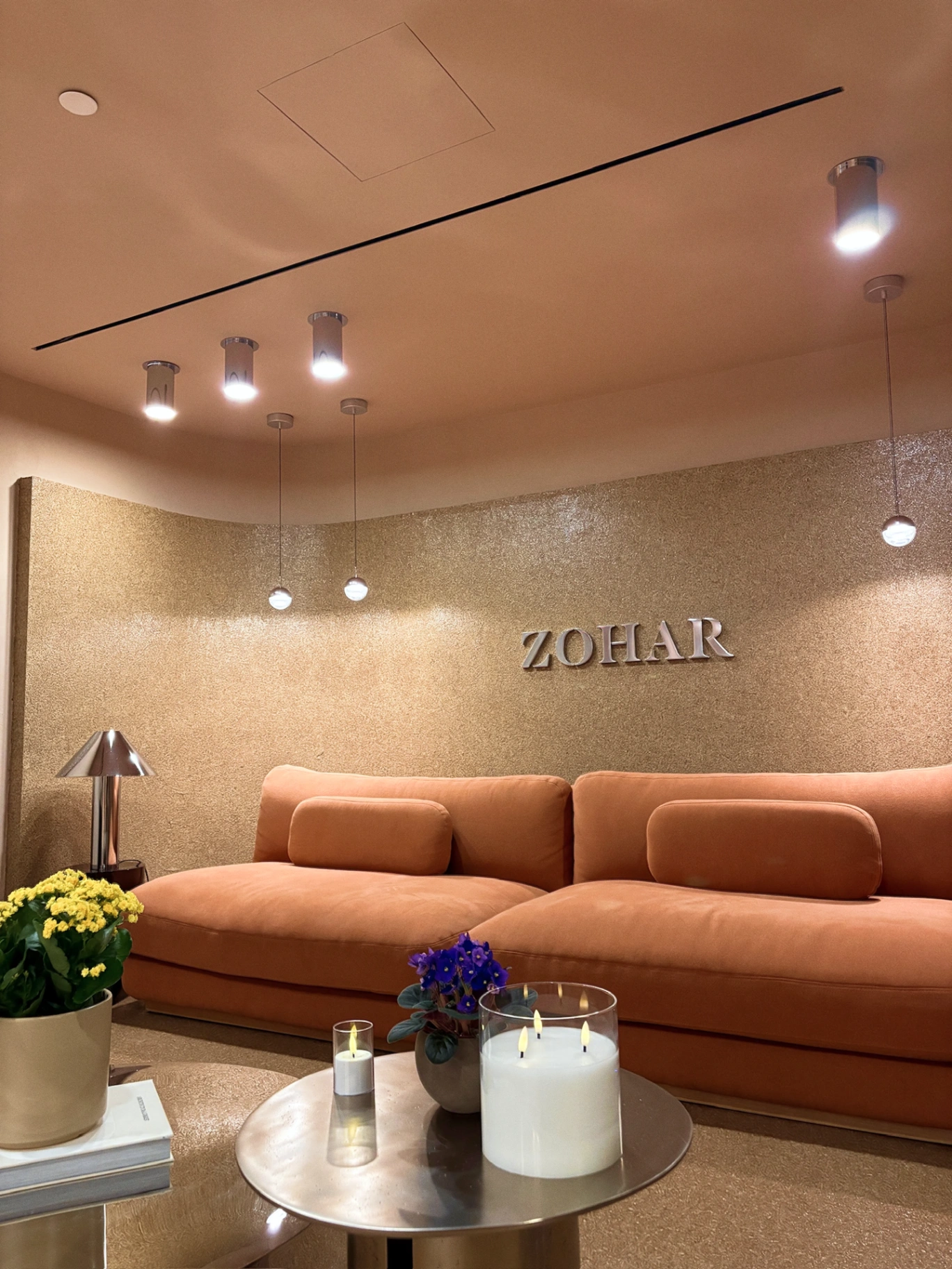 Zohar reception lounge with coral sofas and the ZOHAR signage wall